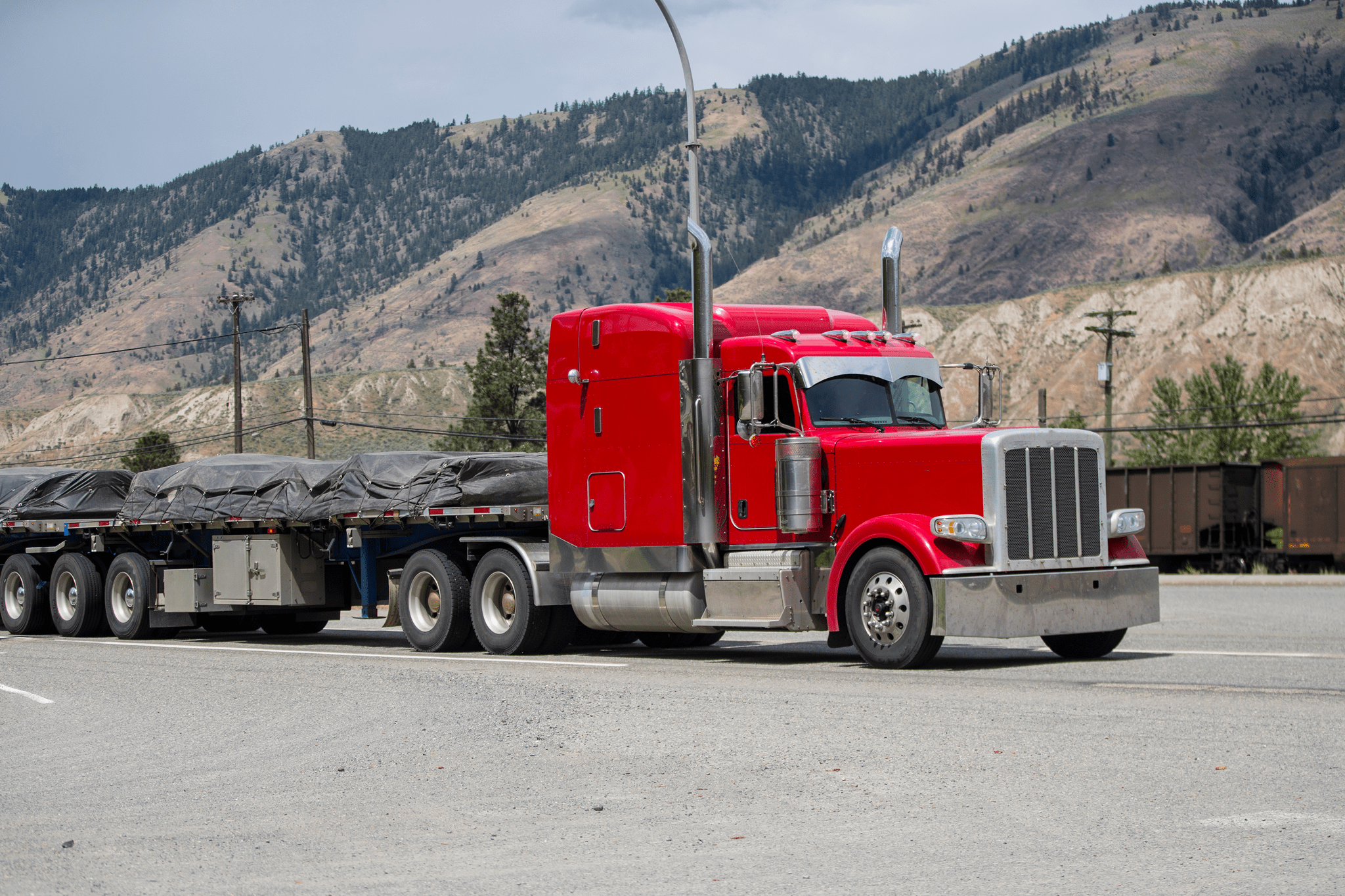 Red semi-truck parked in a mountainous area.