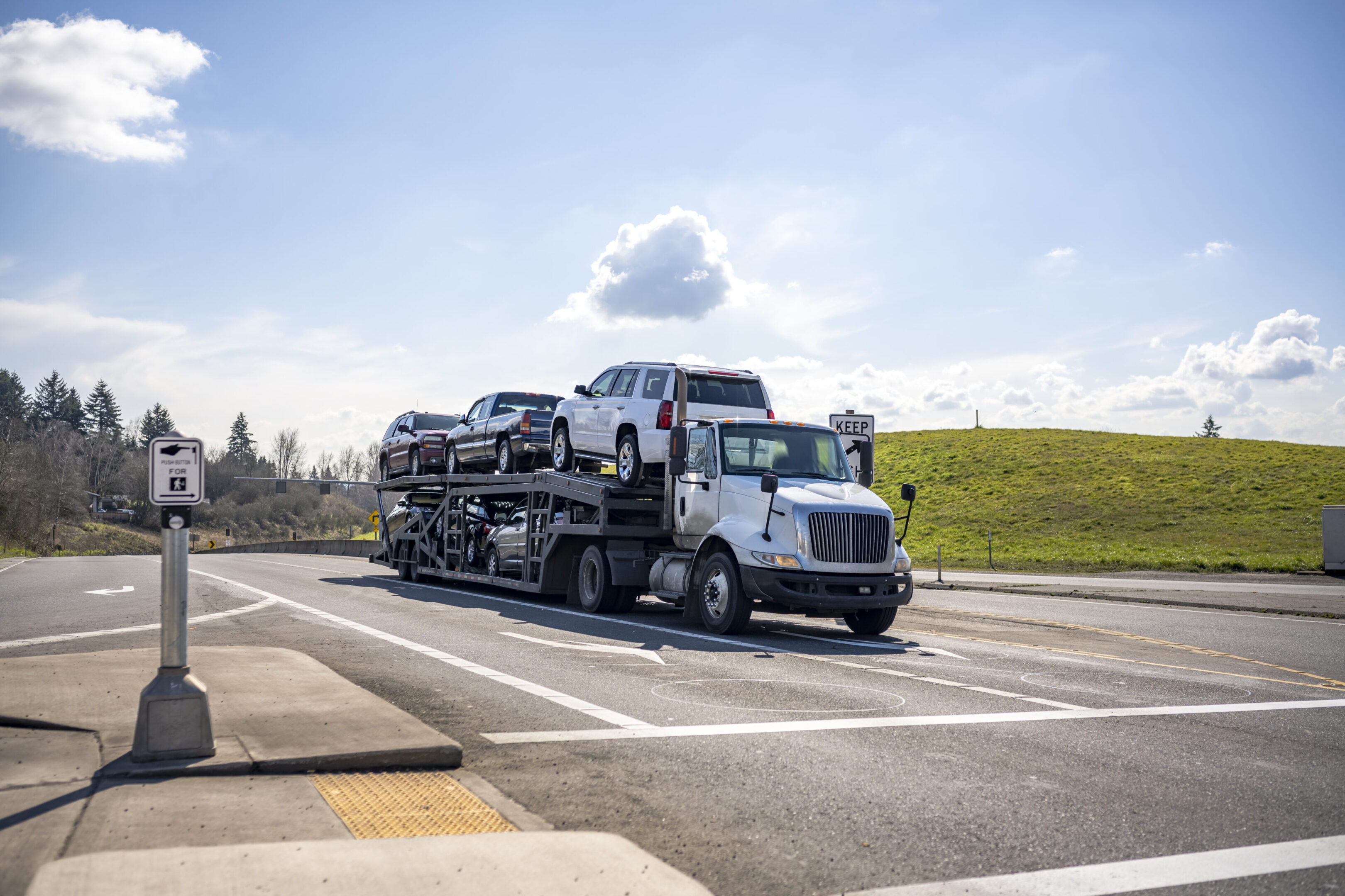 A truck carrying multiple cars on a highway under a clear sky.