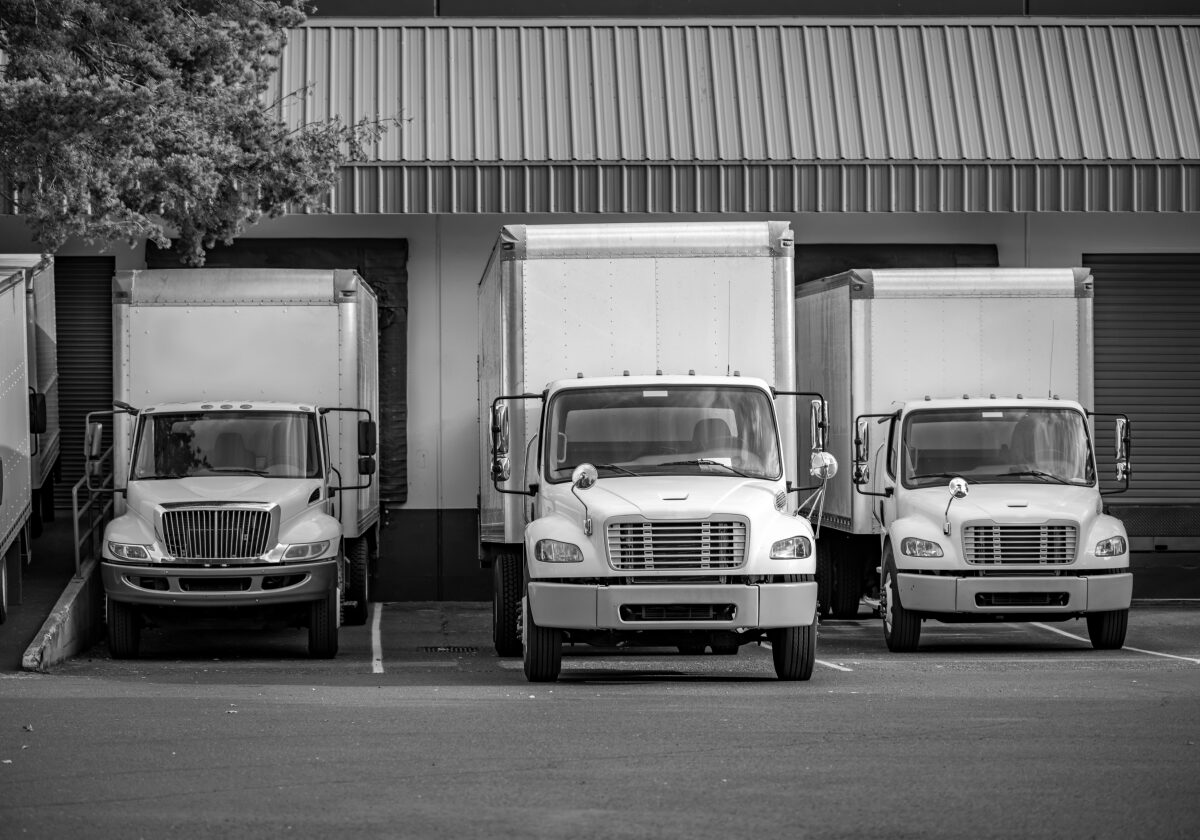 Three delivery trucks parked in front of a loading dock.