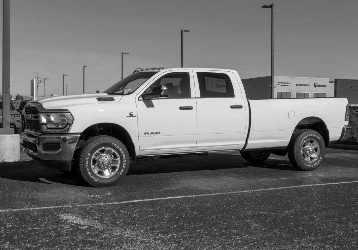 White pickup truck parked in an empty lot under cloudy sky.